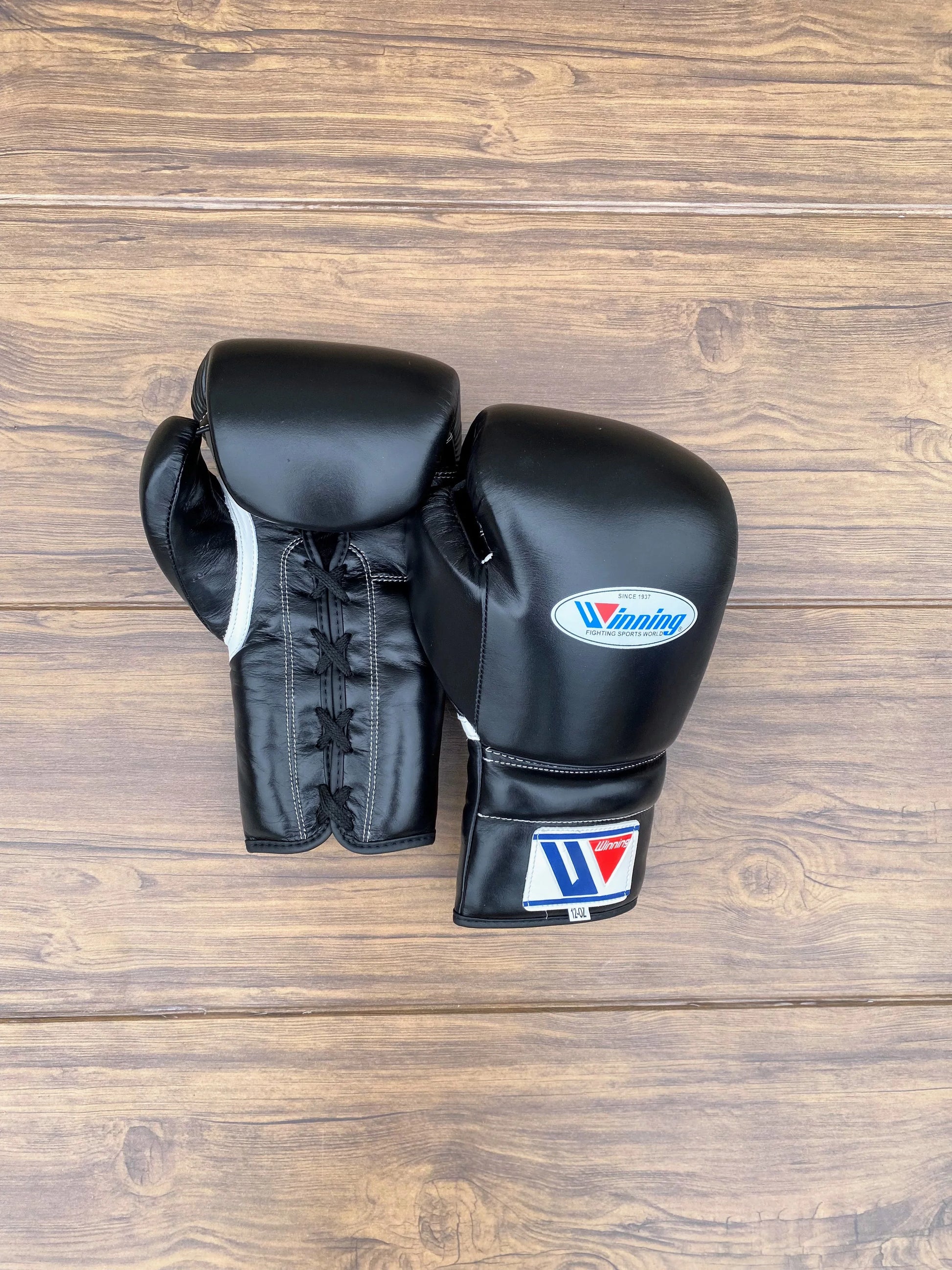 Black Winning boxing gloves with a brand logo on a wooden surface front and back