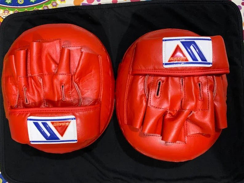 Red boxing gloves with a Winning brand logo on a black background